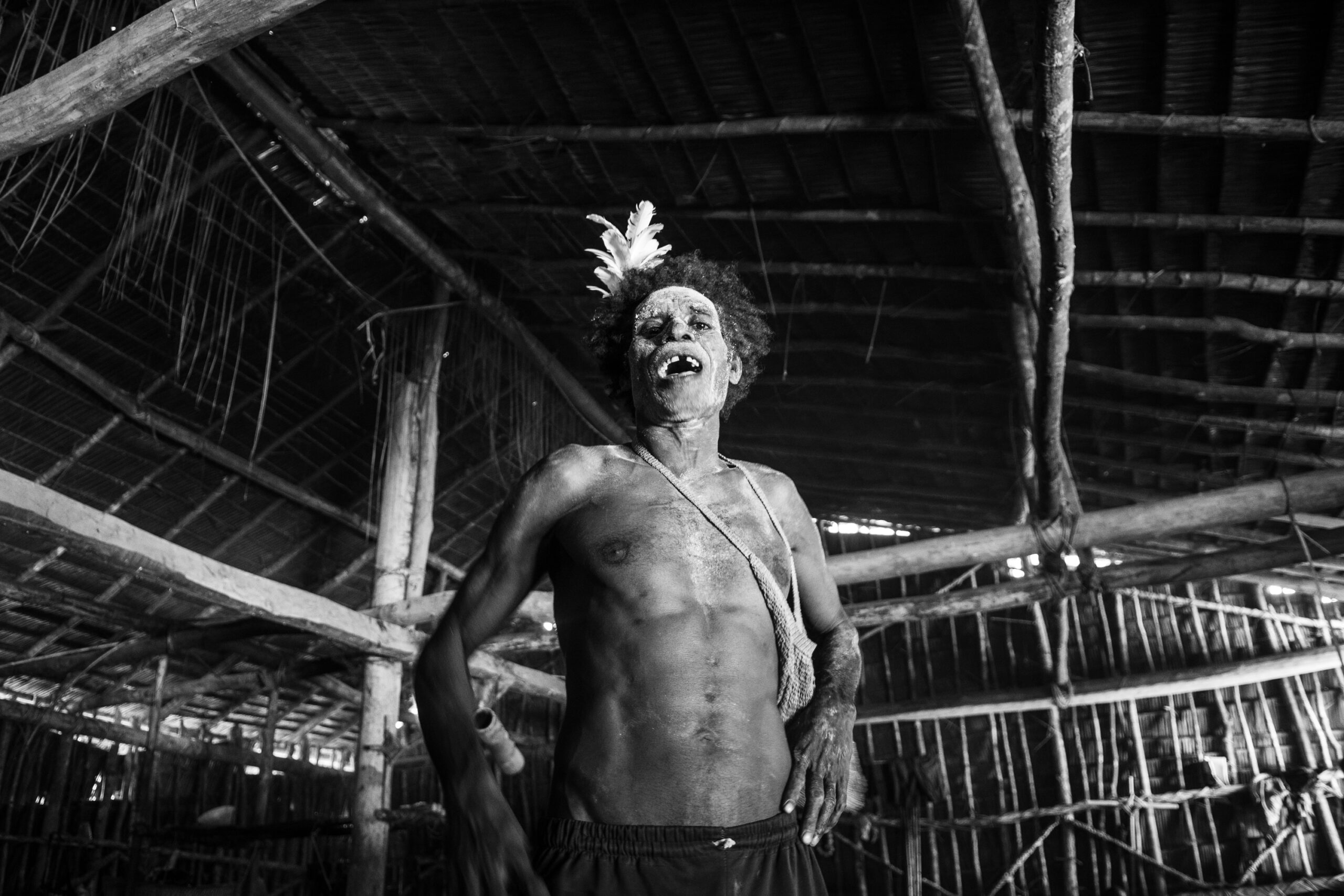 Markus stands in the middle of the traditional house, starting to call the names of the ancestors they are praying for.